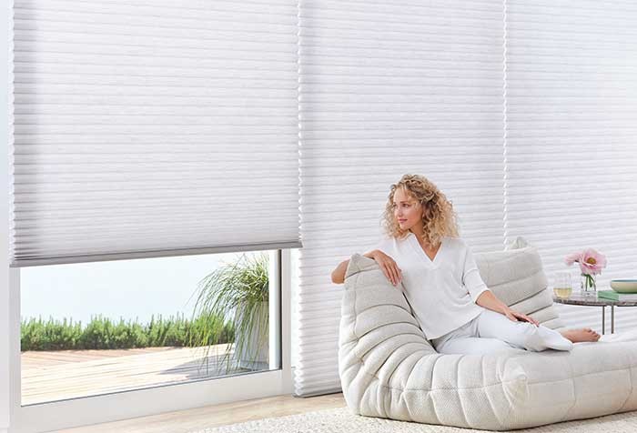 Woman sitting in chair near Duette blinds